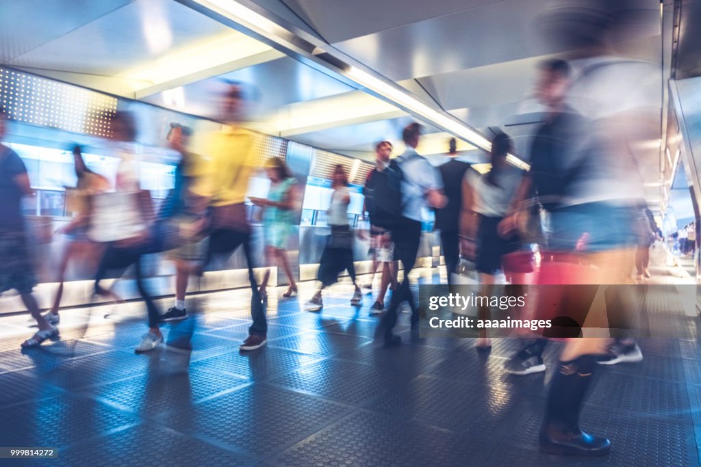Blurred motion of commuters walking through covered footbridge