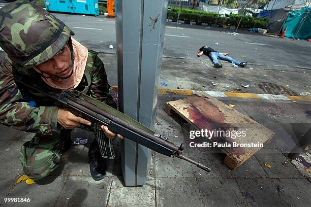 Thai soldier aims his rifle next to the body of a redshirt protester during an early morning attack on the red shirt camp May 19, 2010 in Bangkok, At...