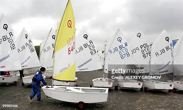 Boy walks next to a small boat during the Cup of Belarus, a sailing competition, in the village of Kachin, 10 km outside Minsk on May 12, 2010. AFP...