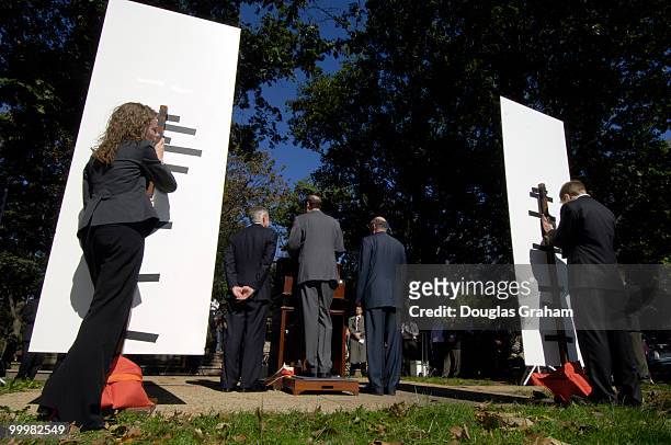 Staffers from Democratic Leader Harry Reid's office Kristine Willie and Nick Weeks hold up signs during a press conference to keep the wind from...