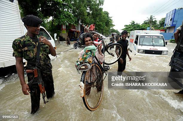 Sri Lankan looks on as a cyclist carries his machine through floodwaters in Seeduwa a suburb of Colombo on May 19, 2010. The military has been...