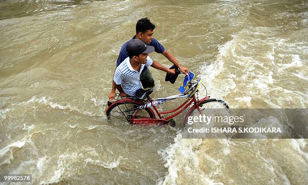 Sri Lankan residents push a bicycle through a flooded stretch of a street in Seeduwa a suburb of Colombo on May 19, 2010. The military has been...