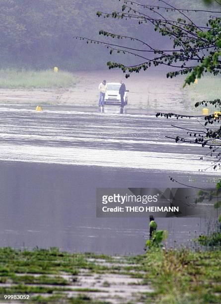 Two men look at the flood water next to their car at the banks of the River Oder on the German-Polish border on May 19, 2010. The death toll from...
