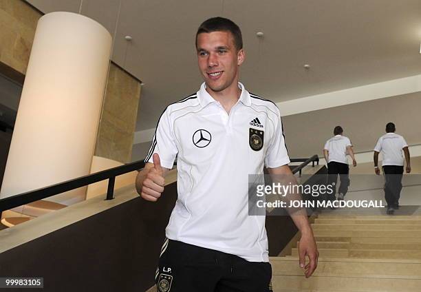Germany's striker Lukas Podolski gives a thumbs up as he goes back to his room after speaking to jounalists at the Verdura Golf and Spa resort, near...