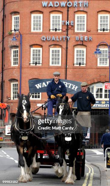 Head horseman Barry Petherick and horseman Martin Whittle pass in front of the Wadworths Brewery building as they deliver beer to local pubs using...