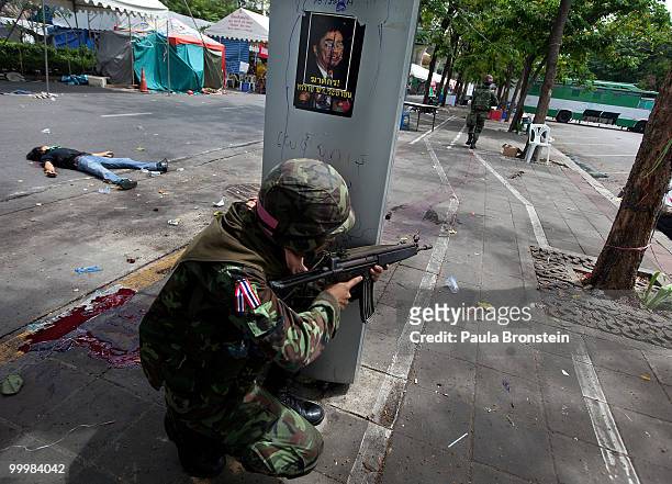 Thai soldier aims his gun next to the body of a redshirt protester during the early morning attack on the red shirt camp May 19, 2010 in Bangkok,...