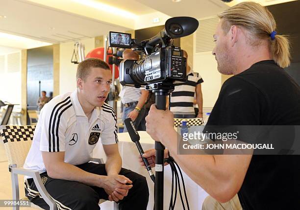 Germany's striker Lukas Podolski speaks to a journalist during a so-called media day at the Verdura Golf and Spa resort, near Sciacca May 19, 2010....