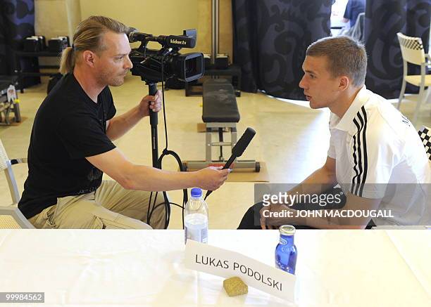 Germany's striker Lukas Podolski speaks to a journalist during a so-called media day at the Verdura Golf and Spa resort, near Sciacca May 19, 2010....