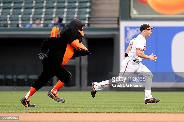 Luke Scott of the Baltimore Orioles races the Orioles mascot "Oriole Bird" before the game against the Kansas City Royals at Camden Yards on May 18,...