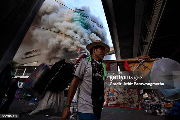 Red Shirt protester carries his belonging inside the devastated red shirt camp as a fire burn at the Central World Shopping Mall on May 19, 2010 in...