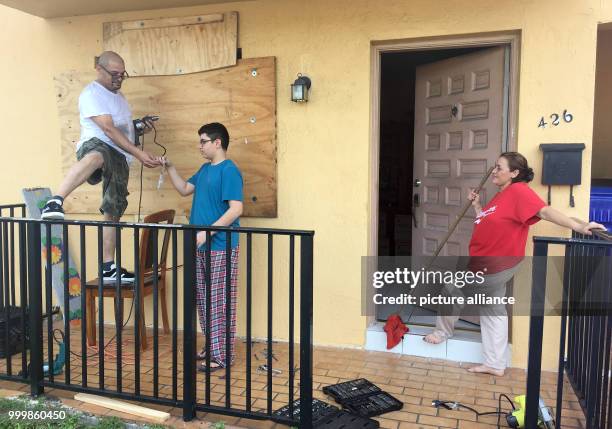 Juan Oviendo , Jonathan Oviendo and Ana Rodriguez nail wood to their house before the arrival of hurricane 'Irma' in Little Havana, Miami, US, 8...