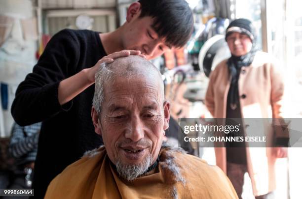 This picture taken on February 27, 2018 shows an ethnic Hui Muslim man having his head shaved in Guanhe, China's Gansu province. - Green-domed...