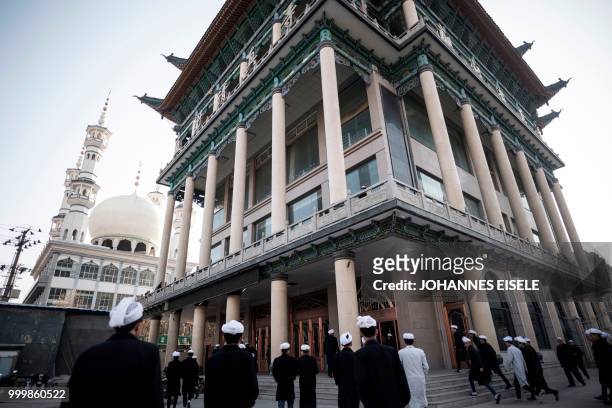 This picture taken on February 27, 2018 shows ethnic Hui Muslim men arriving at a mosque in Guanhe, China's Gansu province. - Green-domed mosques...