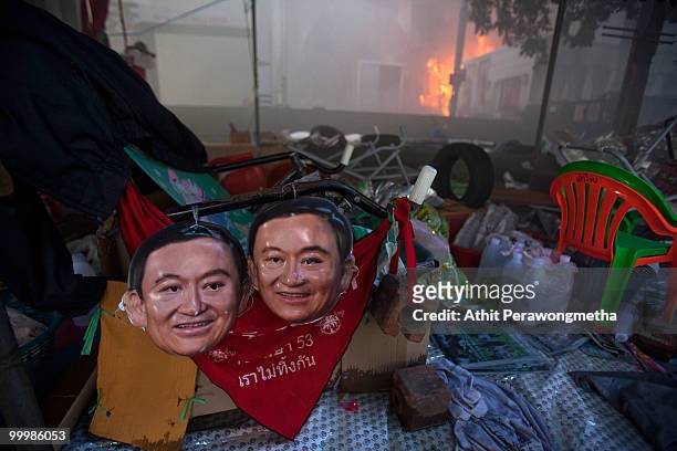 Masks of former Prime Minister Thaksin Shinawatra are seen inside the devastated red shirt camp as a fire burn at the Central World Shopping Mall on...