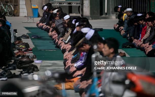 This picture taken on March 2, 2018 shows ethnic Hui Muslim men praying at Nanguan Mosque during Friday prayers in Linxia, China's Gansu province. -...