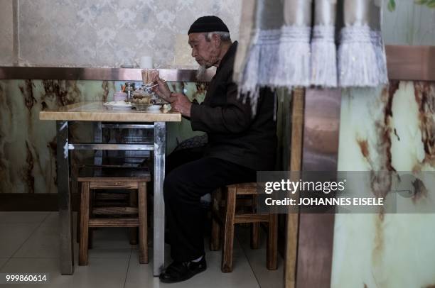 This picture taken on February 27, 2018 shows an ethnic Hui Muslim man eating in a restaurant in Guanhe, China's Gansu province. - Green-domed...