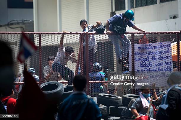 Thai anti-government red shirt protesters climb over a gate at the Bangkok Police General Hospital as Thai military forces move in to their...