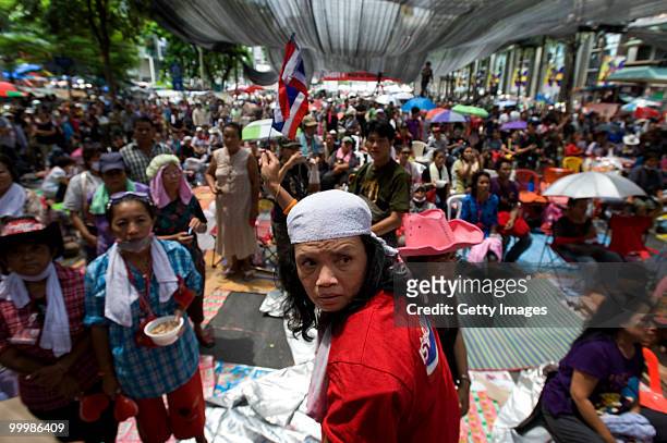 Thai anti-government red shirt protesters stand to listen to their leaders tell them that their protest must end as Thai military forces advance on...
