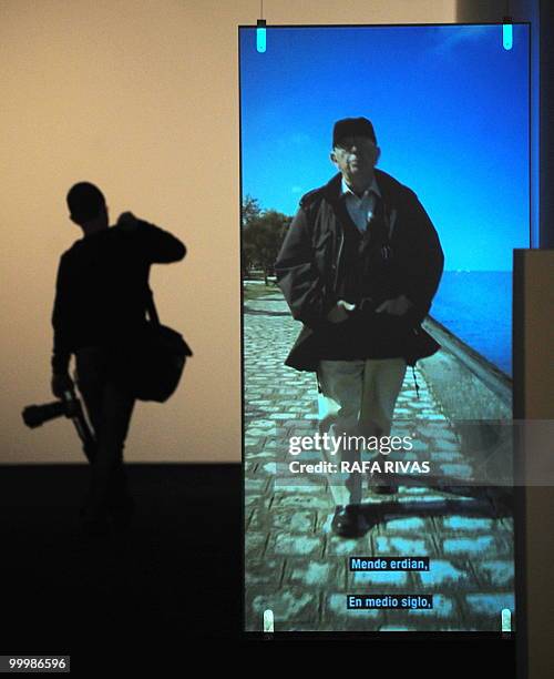 Photographer walks past a screen displaying an image of French photographer Raymond Depardon during the presentation of "Ama Lurra" exhibition at the...