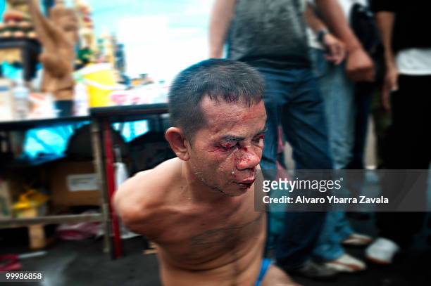 Red shirt protesters hold a prison in their camp, who has been attacked under suspicion of being a member of the army or a sniper, as Thai troops...