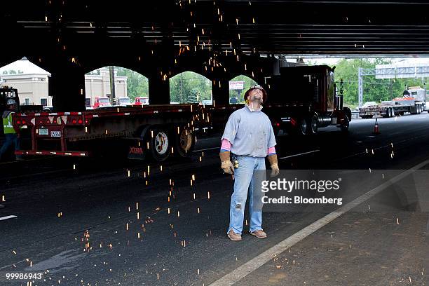 Christian Piazza, an iron worker, watches as sparks fly during the extension of an overpass on the New Jersey Turnpike in Bordentown, New Jersey,...