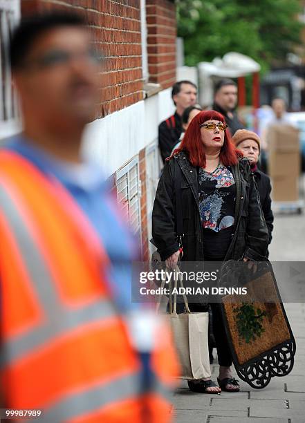 Woman stands to watch firemen tackling a rooftop blaze on a roof above an apartment in London on May 19, 2010. The building was extensively damaged...