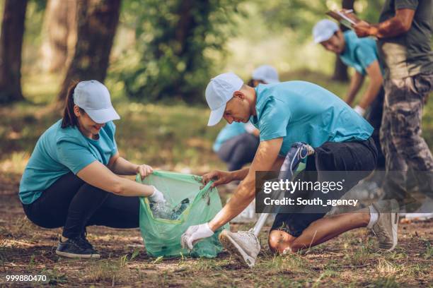 young volunteers picking up trash in public park - south_agency stock pictures, royalty-free photos & images