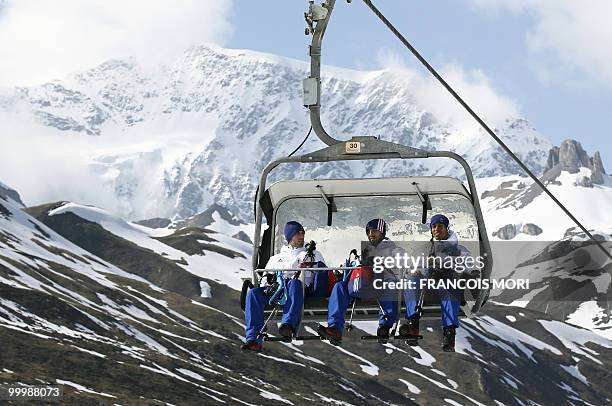 France's football players Anthony Reveillere, Marc Planus and staff member Stephane Diagana sit in a ski lift to reach the Tignes glacier on May 19,...