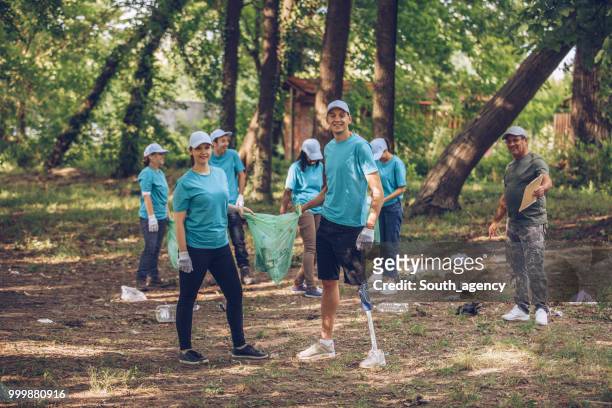 young volunteers picking up trash in park - south_agency stock pictures, royalty-free photos & images