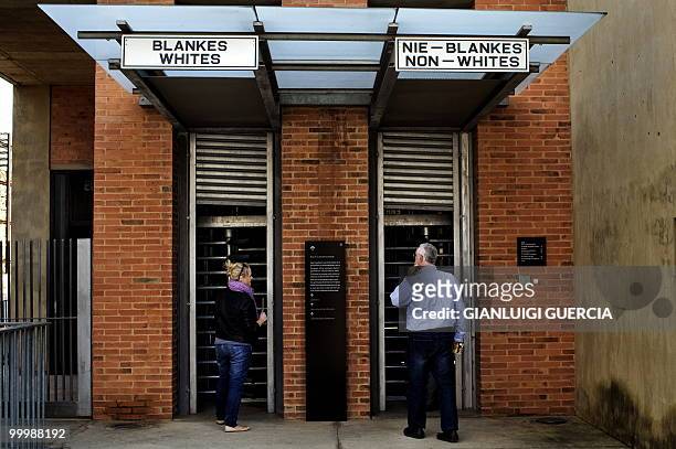 Man and a girl enter through the reproduction of a segregated gate on May 19, 2010 at the Apartheid museum in Johannesburg, South Africa. The...