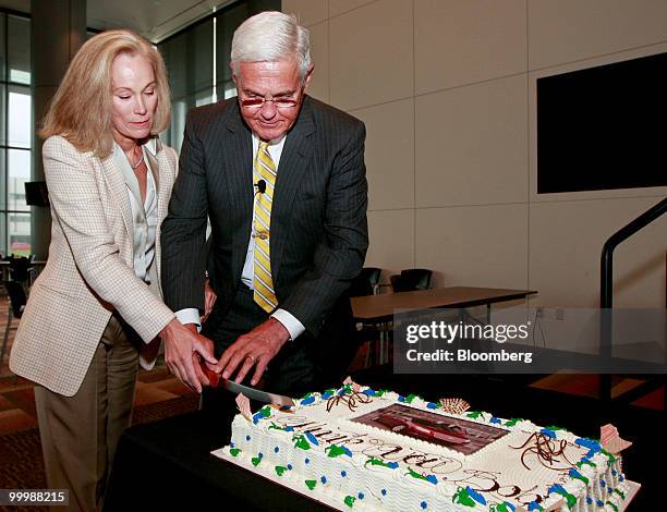 Robert "Bob" Lutz, former vice chairman of General Motors Co. , right, and his wife Denise cut a cake with a photo of a Chevrolet Malibu on it during...