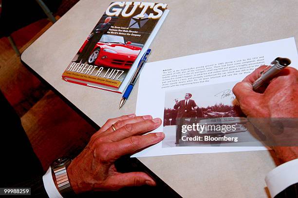 Robert "Bob" Lutz, former vice chairman of General Motors Co. , signs a photograph during a retirement party for Lutz at the GM Vehicle Engineering...