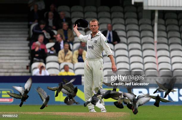 Shaun Udal of Middlesex tries to scare a group of pigeons by waving his hat during the LV County Championship Division Two match between Surrey and...