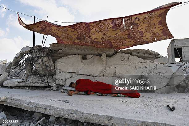 Palestinian man sleeps on the rubble of his house which was demolished by Hamas security forces in Rafah in the southern Gaza Strip on May 19, 2010....