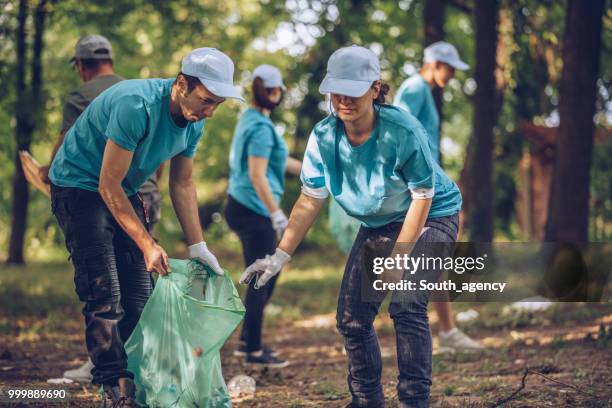 group of young volunteers picking up trash in public park - south_agency stock pictures, royalty-free photos & images