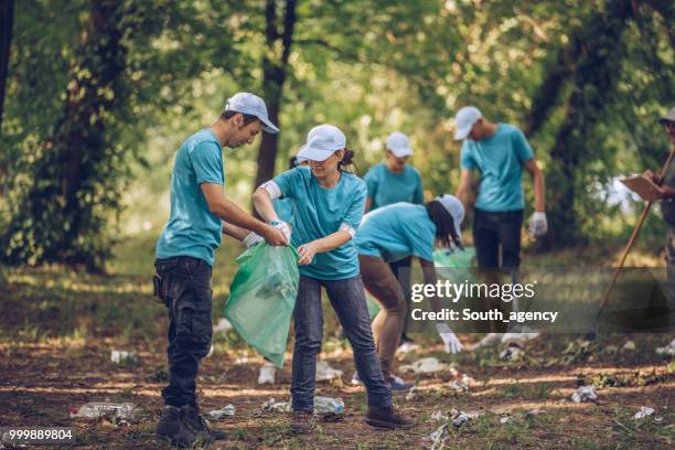 grupo de voluntarios recogiendo basura en parque público - south_agency fotografías e imágenes de stock