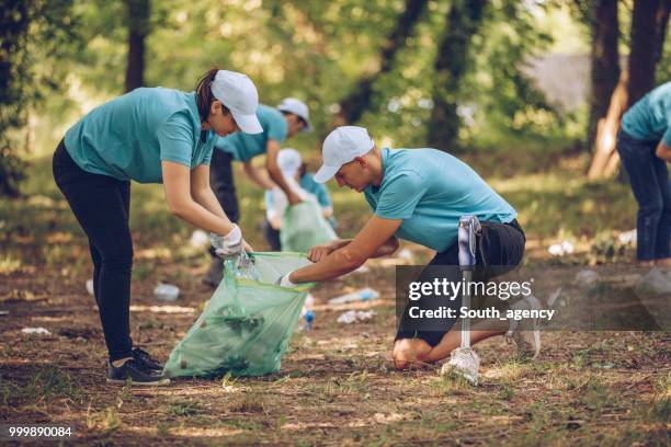 group of young volunteers picking up trash in park - south_agency stock pictures, royalty-free photos & images