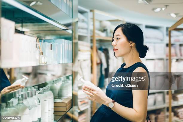 beautiful pregnant woman shopping for beauty products in shopping mall - perfumería fotografías e imágenes de stock
