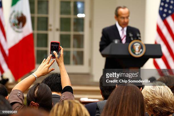 Reporter with the Mexican press uses her BlackBerry to take a photograph of Mexican President Felipe Calderon while he holds a joint press conference...