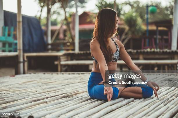 woman doing yoga meditation exercises at the beach - south_agency stock pictures, royalty-free photos & images