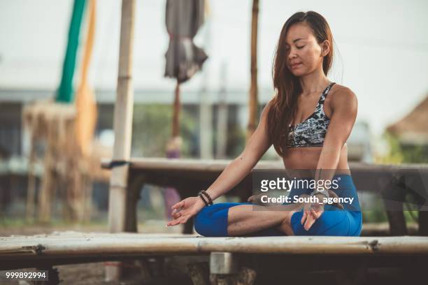 woman doing yoga meditation and stretching exercises - south_agency stock pictures, royalty-free photos & images