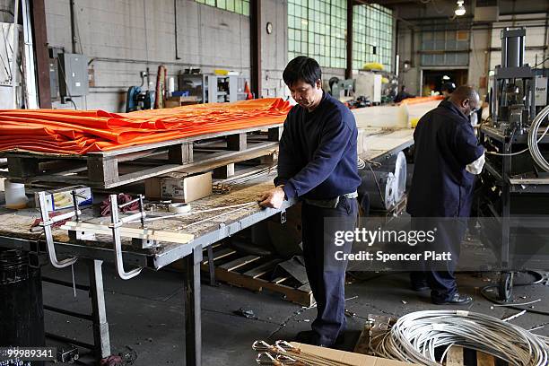 Worker at Slickbar Products, a company that makes oil booms and other products designed to clean up oil spills, manufactures an oil boom on May 19,...