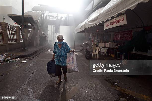 Lone red shirt anti-government protester carries her belongings after Thai military forces cleared the main rally site inside the red shirt camp on...