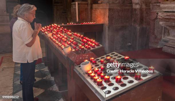 Faithful pray before lit candles placed in front a figure of Our Lady of Fatima in Sao Domingos church on July 13, 2018 in Lisbon, Portugal. Sao...