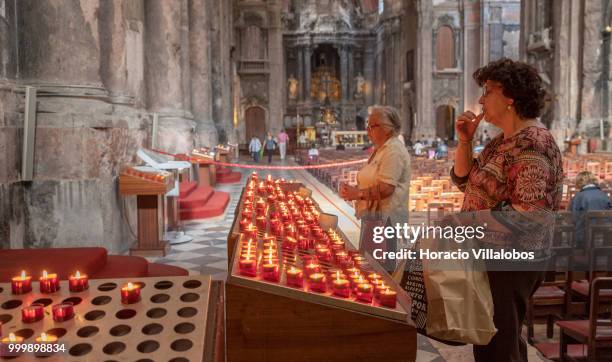 Faithful pray before lit candles placed in front a figure of Our Lady of Fatima in Sao Domingos church on July 13, 2018 in Lisbon, Portugal. Sao...