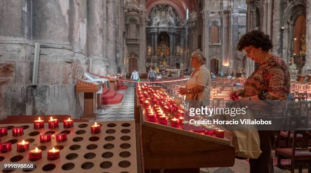 Faithful pray before lit candles placed in front a figure of Our Lady of Fatima in Sao Domingos church on July 13, 2018 in Lisbon, Portugal. Sao...