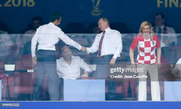 President of France Emmanuel Macron shakes hands with President of Russia Vladimir Putin while President of Croatia Kolinda Grabar-Kitarovic looks on...