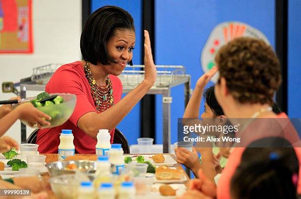 First lady Michelle Obama high fives with Head Start student Wendy Zacarias ) after Mrs. Obama convinced Zacarias to drink milk during lunch as she...