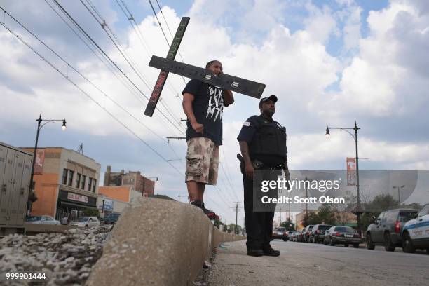 Joseph Saunders carries a cross during a protest of the shooting death of 37-year-old Harith Augustus in the South Shore neighborhood on July 15,...