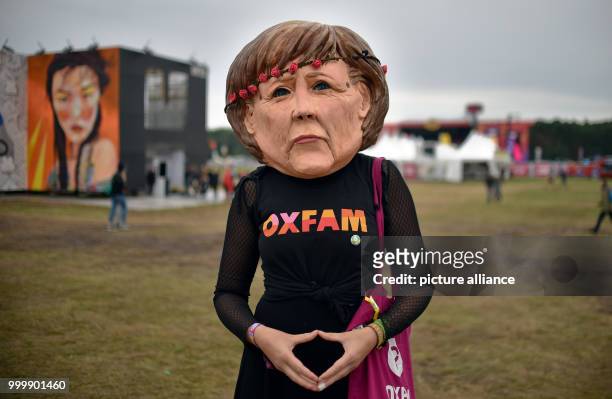 An activist wears a mask of the German chancellor Angela Merkel and an Oxfam shirt at the Lollapalooza festival in Hoppegarten, Germany, 9 September...